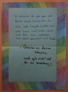 Ein handgeschriebener Willkommensgruß eines Schülers bzw. einer Schülerin für neue Mitschüler:innen. Zu lesen sind persönliche Wünsche zum Start an unserer Schule.